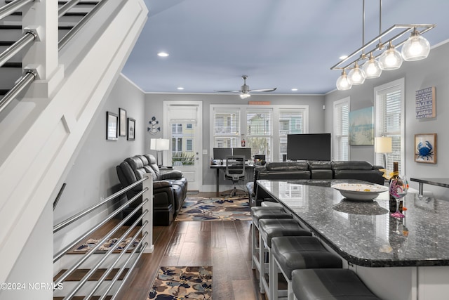 interior space with ceiling fan, ornamental molding, and dark wood-type flooring