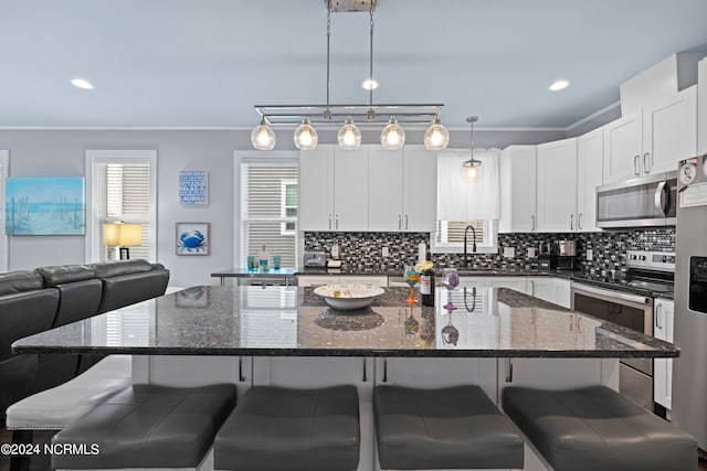 kitchen with stainless steel appliances, backsplash, a center island, and decorative light fixtures