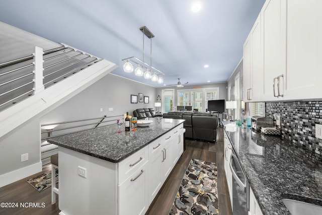 kitchen with decorative light fixtures, dark hardwood / wood-style flooring, a breakfast bar, a center island, and ceiling fan