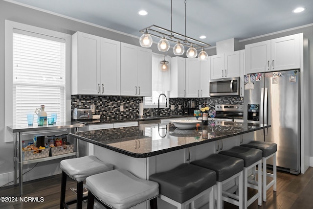 kitchen with hanging light fixtures, stainless steel appliances, a kitchen island, and white cabinetry