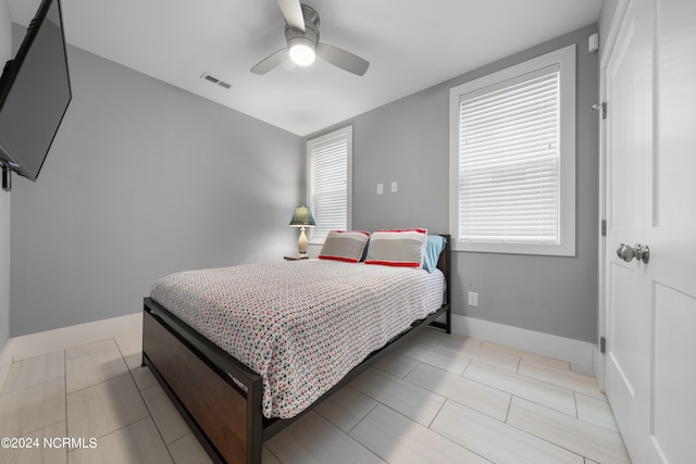 tiled bedroom featuring multiple windows and ceiling fan