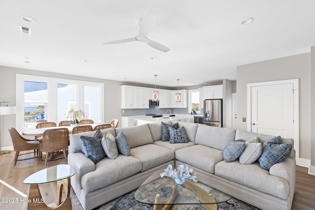 living room with ceiling fan and light hardwood / wood-style flooring