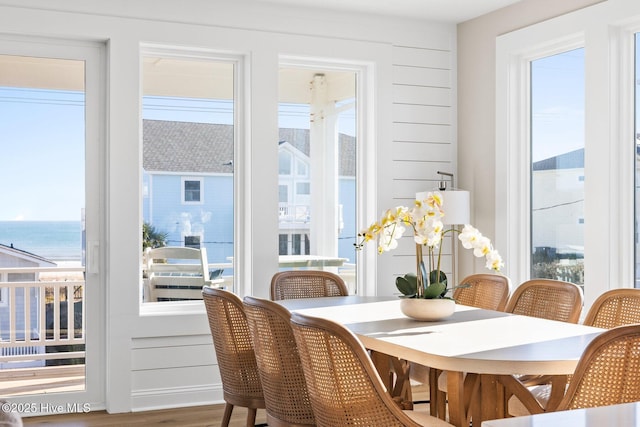 dining area featuring hardwood / wood-style flooring, wood walls, and a water view