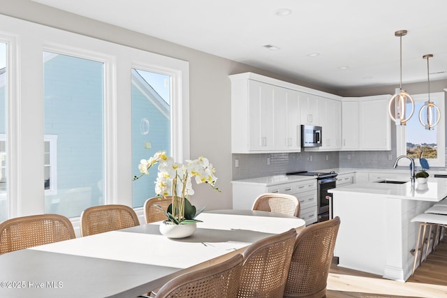 kitchen with white cabinetry, appliances with stainless steel finishes, decorative light fixtures, and sink