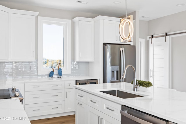 kitchen featuring sink, stainless steel appliances, a barn door, and white cabinets