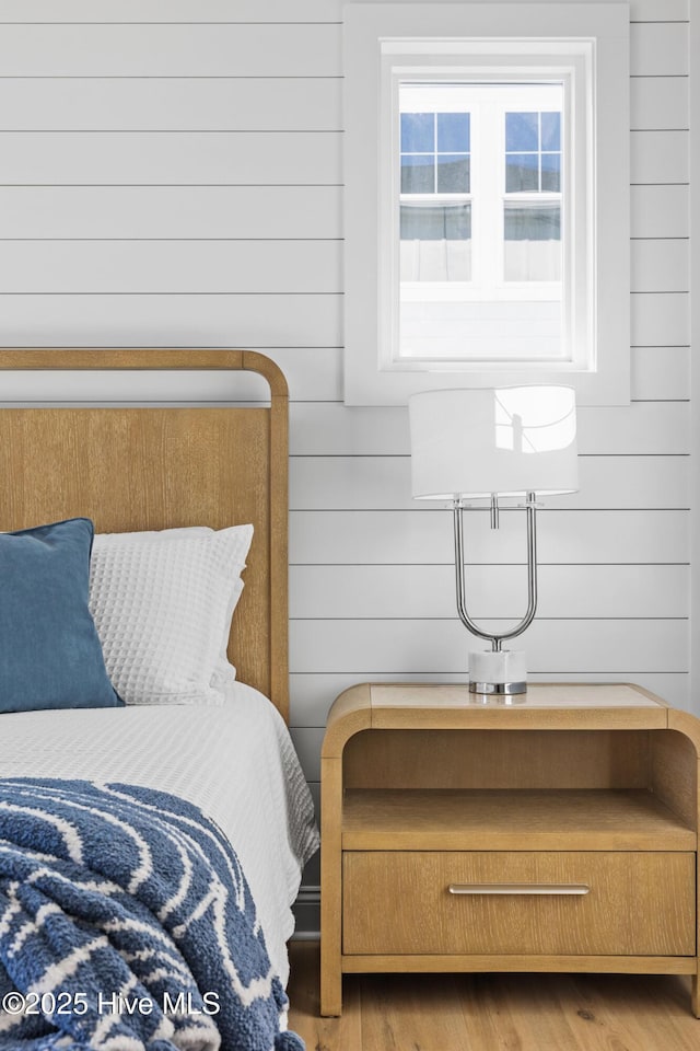 bedroom featuring light hardwood / wood-style flooring and wooden walls