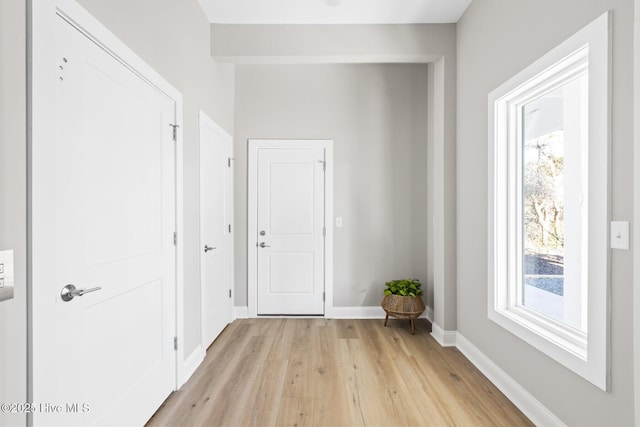 corridor with plenty of natural light and light hardwood / wood-style floors