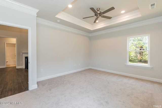 empty room with ornamental molding, a ceiling fan, carpet floors, baseboards, and a tray ceiling