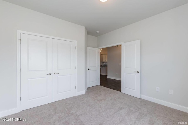 unfurnished bedroom featuring dark colored carpet, baseboards, and a closet