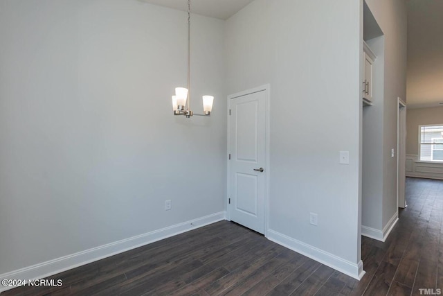 unfurnished dining area with a chandelier, dark wood finished floors, and baseboards