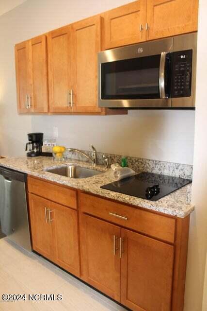 kitchen featuring sink, light stone counters, stainless steel appliances, and light tile flooring