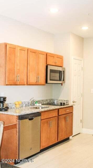 kitchen featuring appliances with stainless steel finishes, light stone counters, and sink