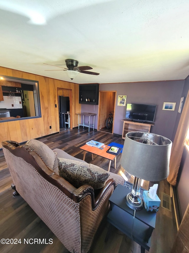 living room with ceiling fan and dark wood-type flooring