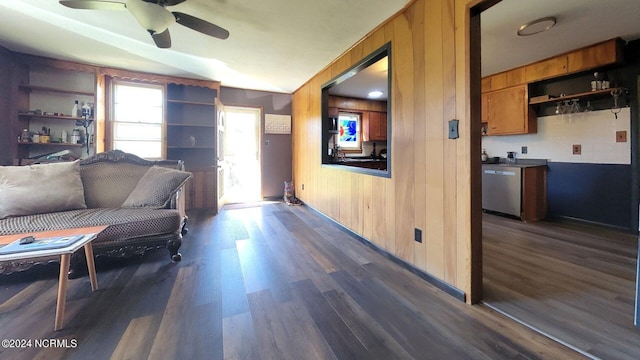 living room with dark hardwood / wood-style flooring, ceiling fan, built in features, and wooden walls