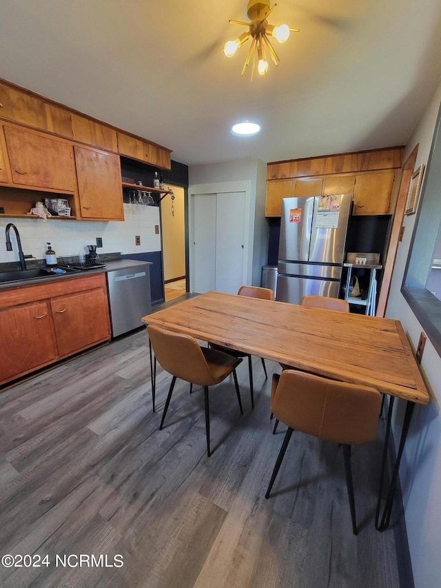 kitchen featuring appliances with stainless steel finishes, sink, backsplash, dark hardwood / wood-style floors, and an inviting chandelier