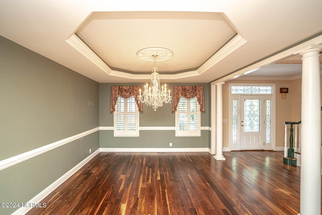 spare room with ornate columns, a notable chandelier, a raised ceiling, and dark hardwood / wood-style flooring