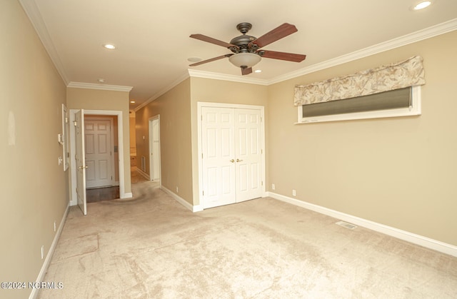 unfurnished bedroom featuring ceiling fan, a closet, crown molding, and light carpet