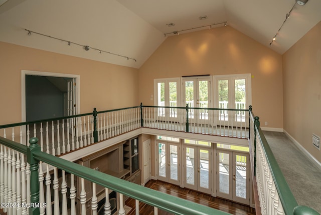 interior space featuring high vaulted ceiling, carpet floors, and rail lighting