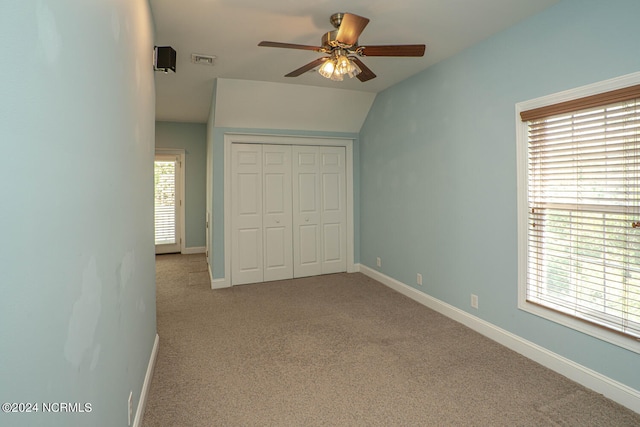 unfurnished bedroom featuring light carpet, lofted ceiling, and multiple windows