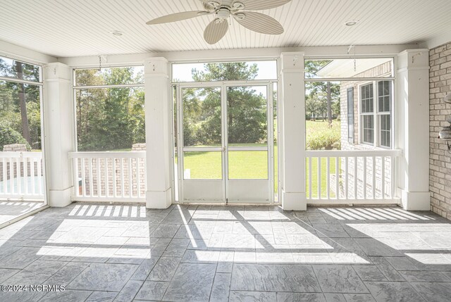 unfurnished sunroom featuring wooden ceiling, ceiling fan, and plenty of natural light