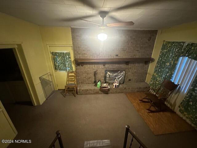 interior space featuring ceiling fan, brick wall, and a brick fireplace