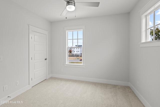 spare room with light carpet, ceiling fan, and a wealth of natural light