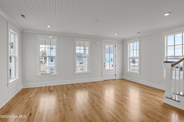 unfurnished living room with light hardwood / wood-style floors, a wealth of natural light, and ornamental molding