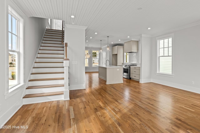 unfurnished living room with wood-type flooring, sink, wood ceiling, and ornamental molding