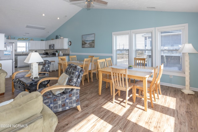 dining space featuring high vaulted ceiling, ceiling fan, and light wood-type flooring