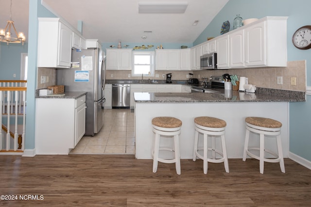 kitchen featuring an inviting chandelier, tasteful backsplash, stainless steel appliances, pendant lighting, and vaulted ceiling