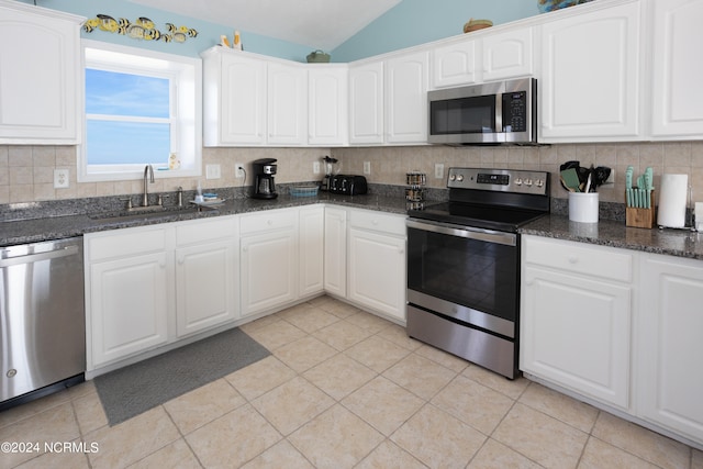 kitchen with vaulted ceiling, stainless steel appliances, and white cabinetry