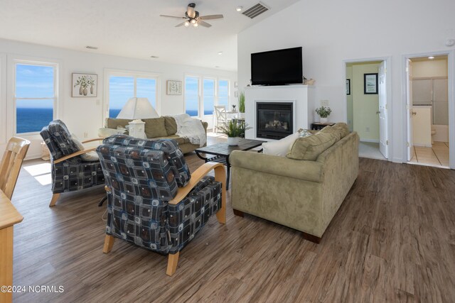 living room featuring ceiling fan, a water view, dark wood-type flooring, and high vaulted ceiling