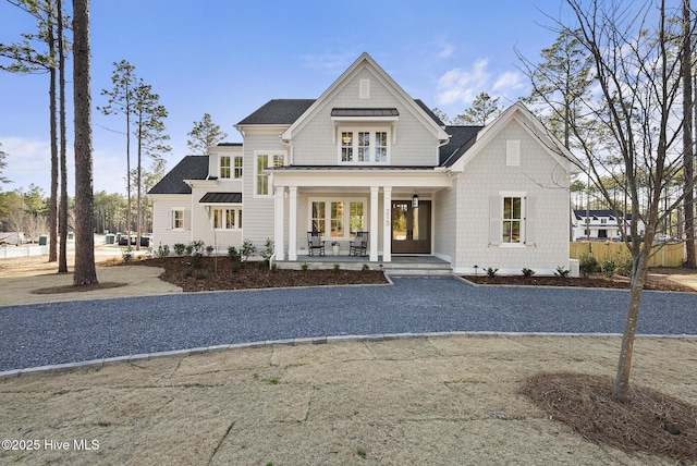 shingle-style home with a porch, fence, and roof with shingles