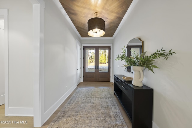 doorway to outside with light wood-style flooring, french doors, baseboards, and ornamental molding