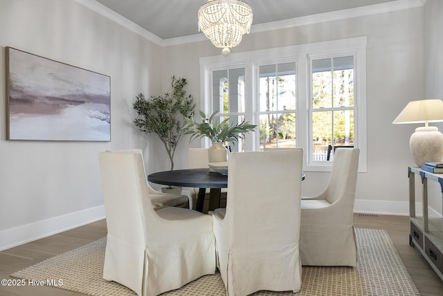 dining space featuring crown molding, wood finished floors, and baseboards