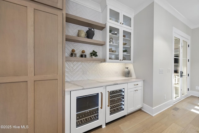 bar with beverage cooler, backsplash, baseboards, and light wood-style floors