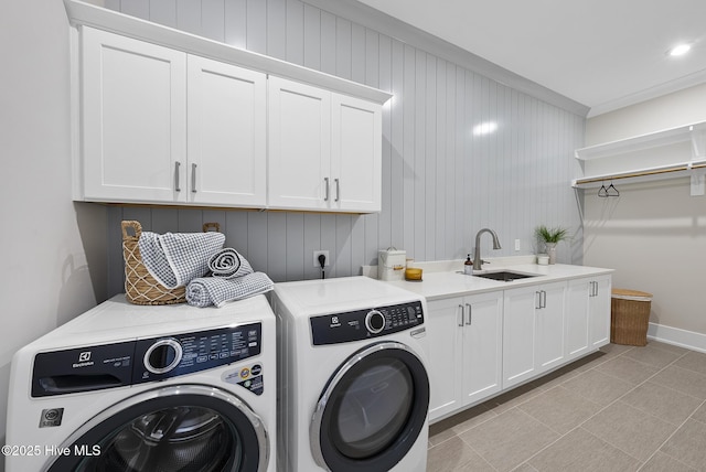 laundry area featuring baseboards, light tile patterned flooring, cabinet space, a sink, and washer and clothes dryer