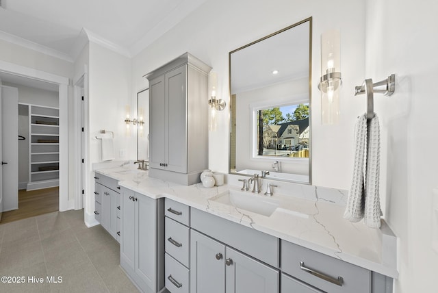 bathroom with double vanity, ornamental molding, tile patterned flooring, a sink, and a spacious closet