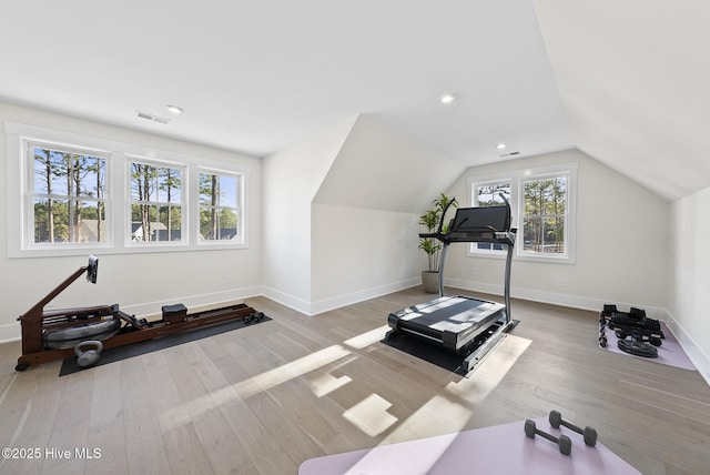 workout area featuring visible vents, baseboards, wood finished floors, and vaulted ceiling