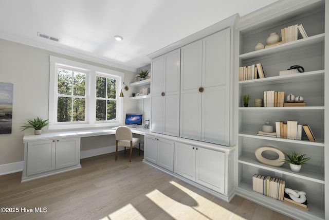 office area with baseboards, visible vents, built in study area, light wood-style flooring, and ornamental molding