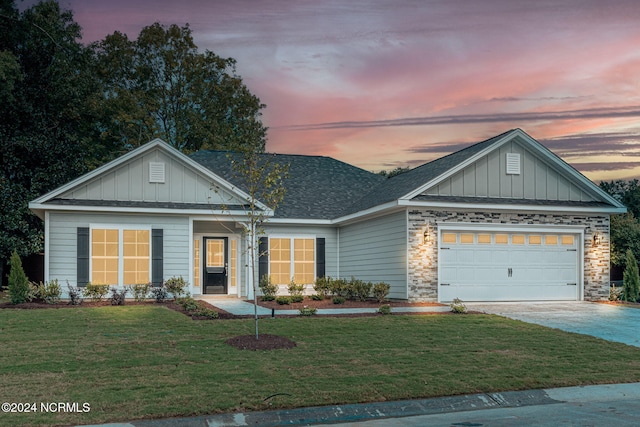 view of front facade featuring board and batten siding, driveway, a lawn, roof with shingles, and a garage