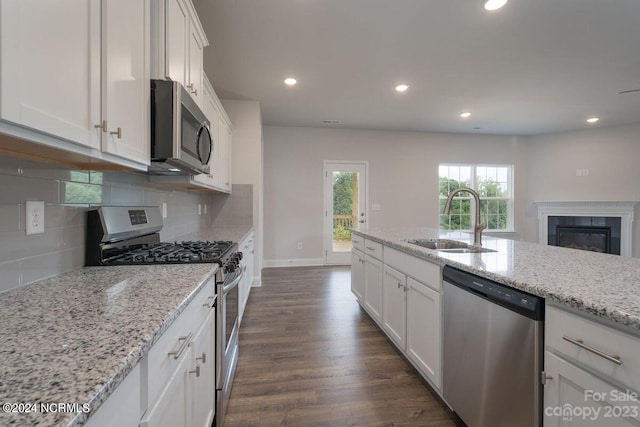 kitchen with dark hardwood / wood-style flooring, sink, light stone counters, stainless steel appliances, and white cabinets