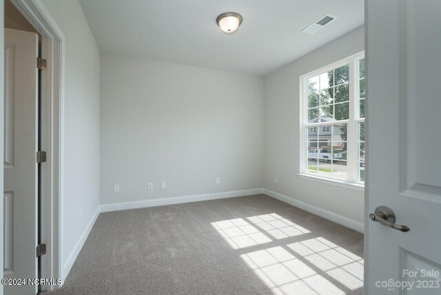 carpeted empty room with visible vents and baseboards