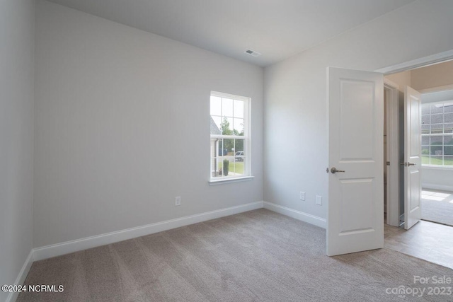 empty room with baseboards, carpet floors, and visible vents