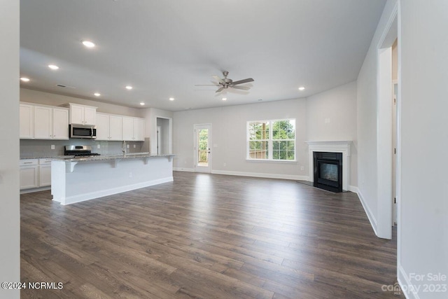 unfurnished living room with ceiling fan, sink, and dark hardwood / wood-style floors