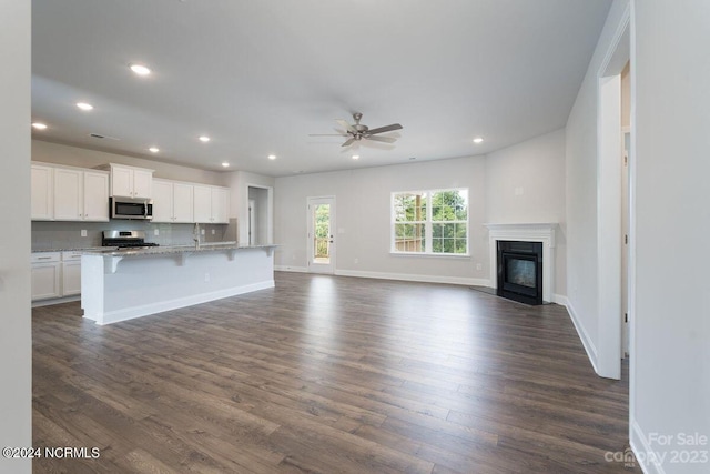 unfurnished living room with dark wood-type flooring, baseboards, ceiling fan, and recessed lighting
