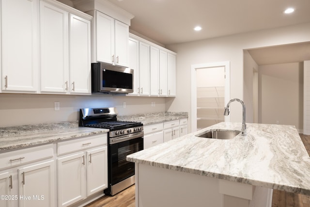 kitchen featuring a center island with sink, white cabinetry, stainless steel appliances, and sink