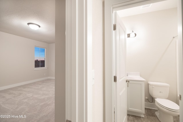 bathroom featuring a textured ceiling, toilet, and vanity