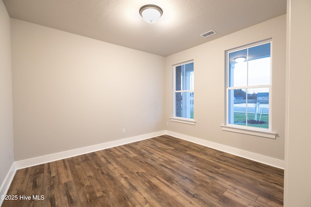 unfurnished room with a textured ceiling and dark hardwood / wood-style flooring