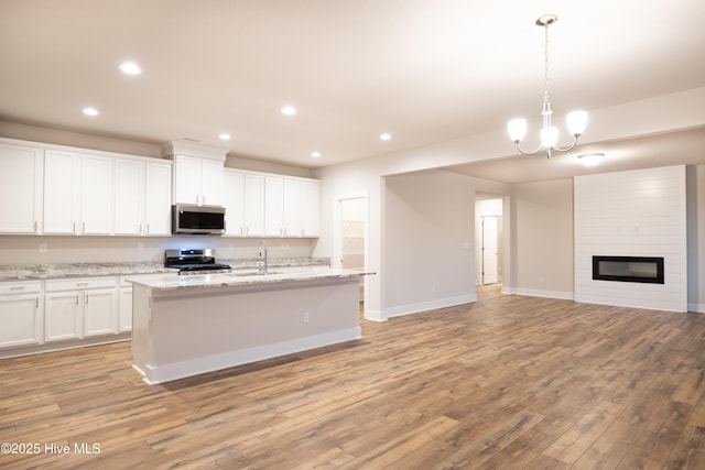 kitchen with stainless steel appliances, pendant lighting, white cabinets, and light stone counters